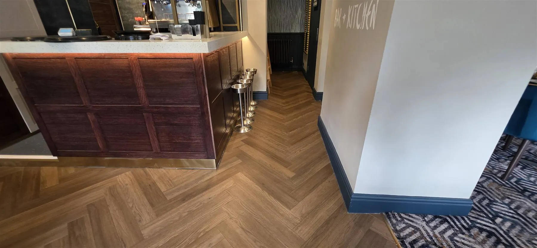Karndean Art Select herringbone running cleanly around the timber-panelled bar counter