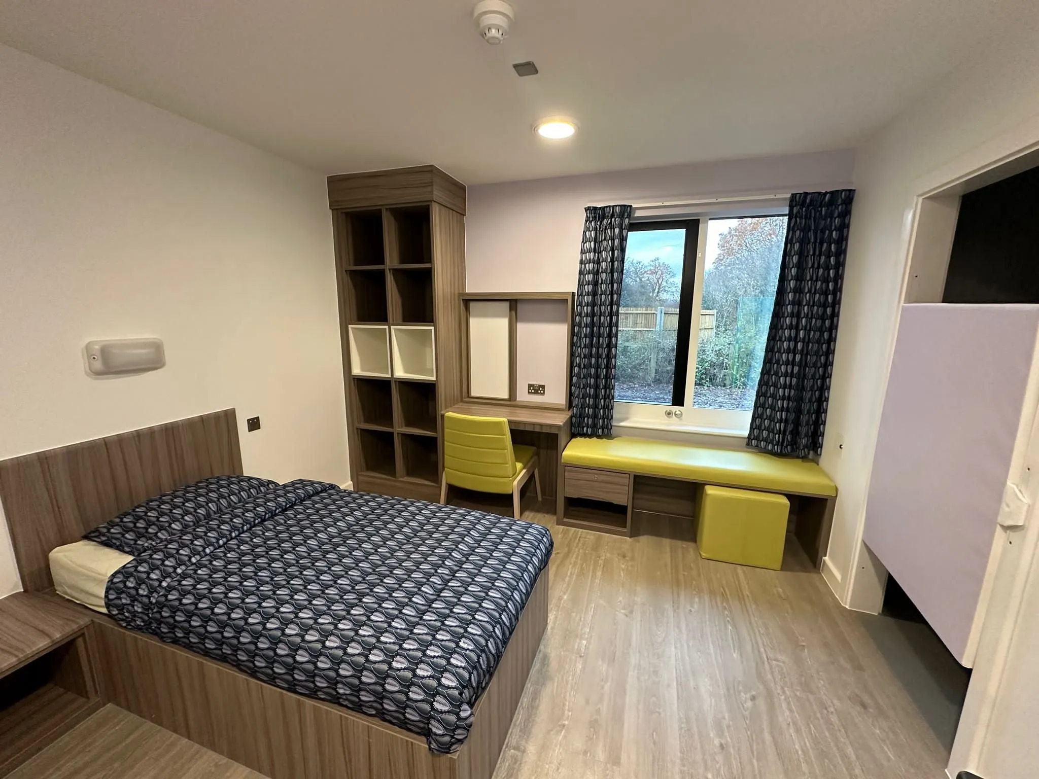 Wood-effect safety vinyl in a bedroom with a built-in desk and window seat