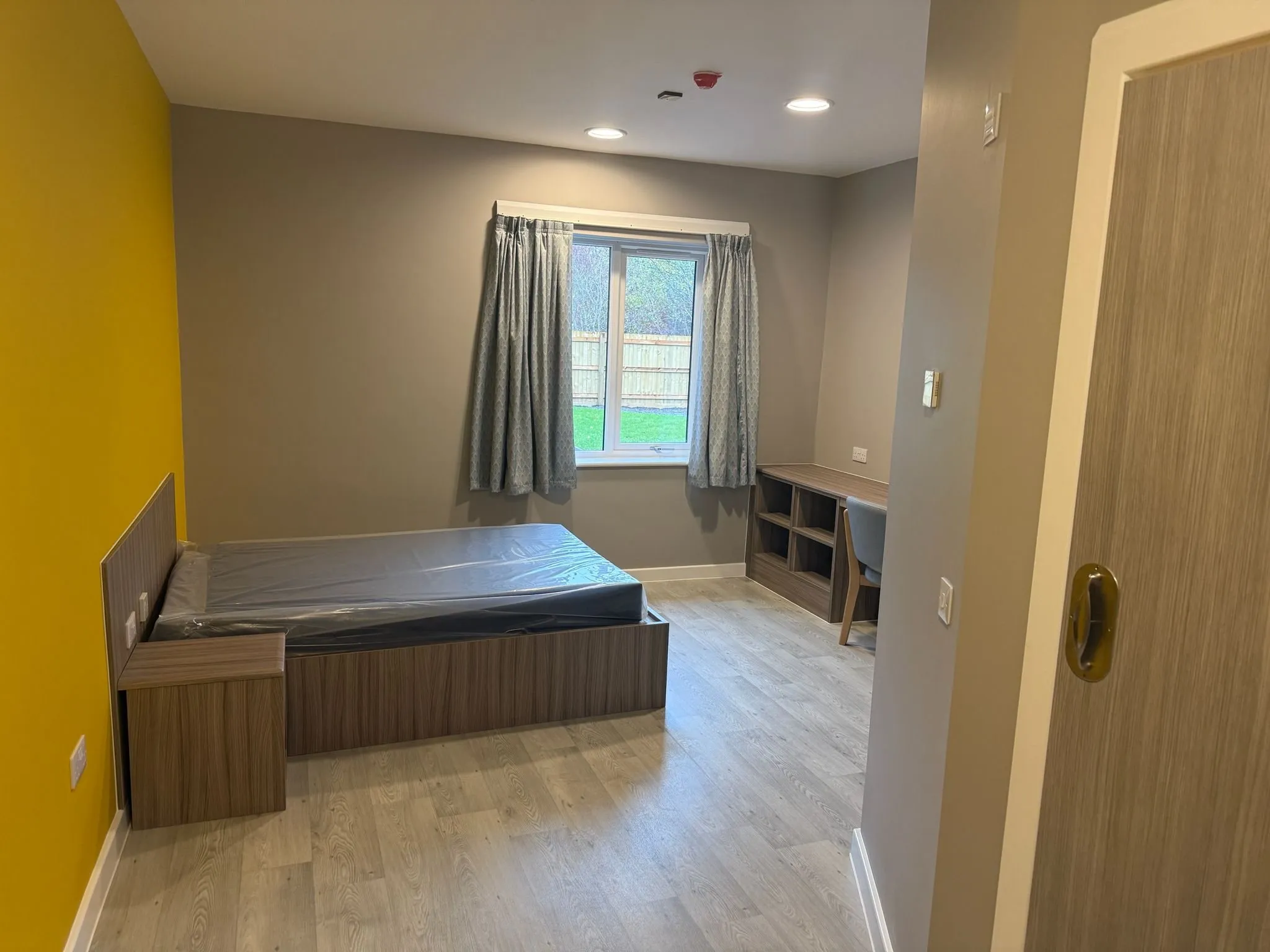 Polyflor Forest FX wood-effect sheet vinyl in a bedroom with a yellow feature wall