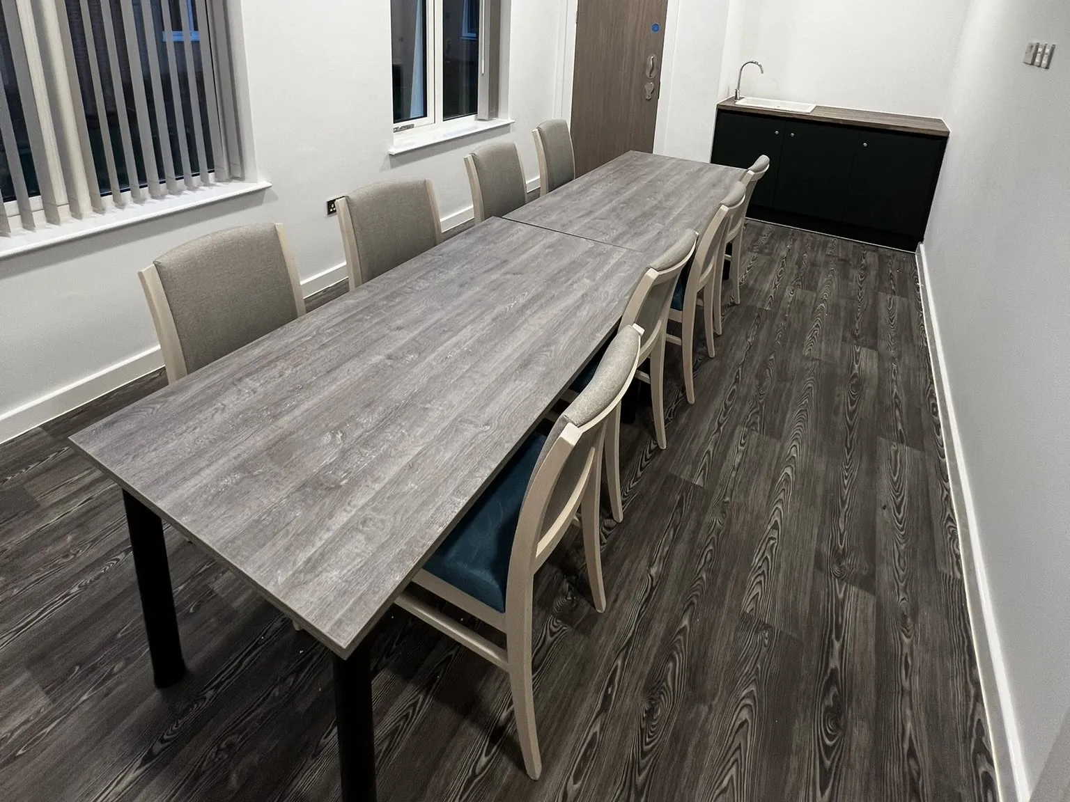 Darker wood-effect safety vinyl beneath the long table in the dining room