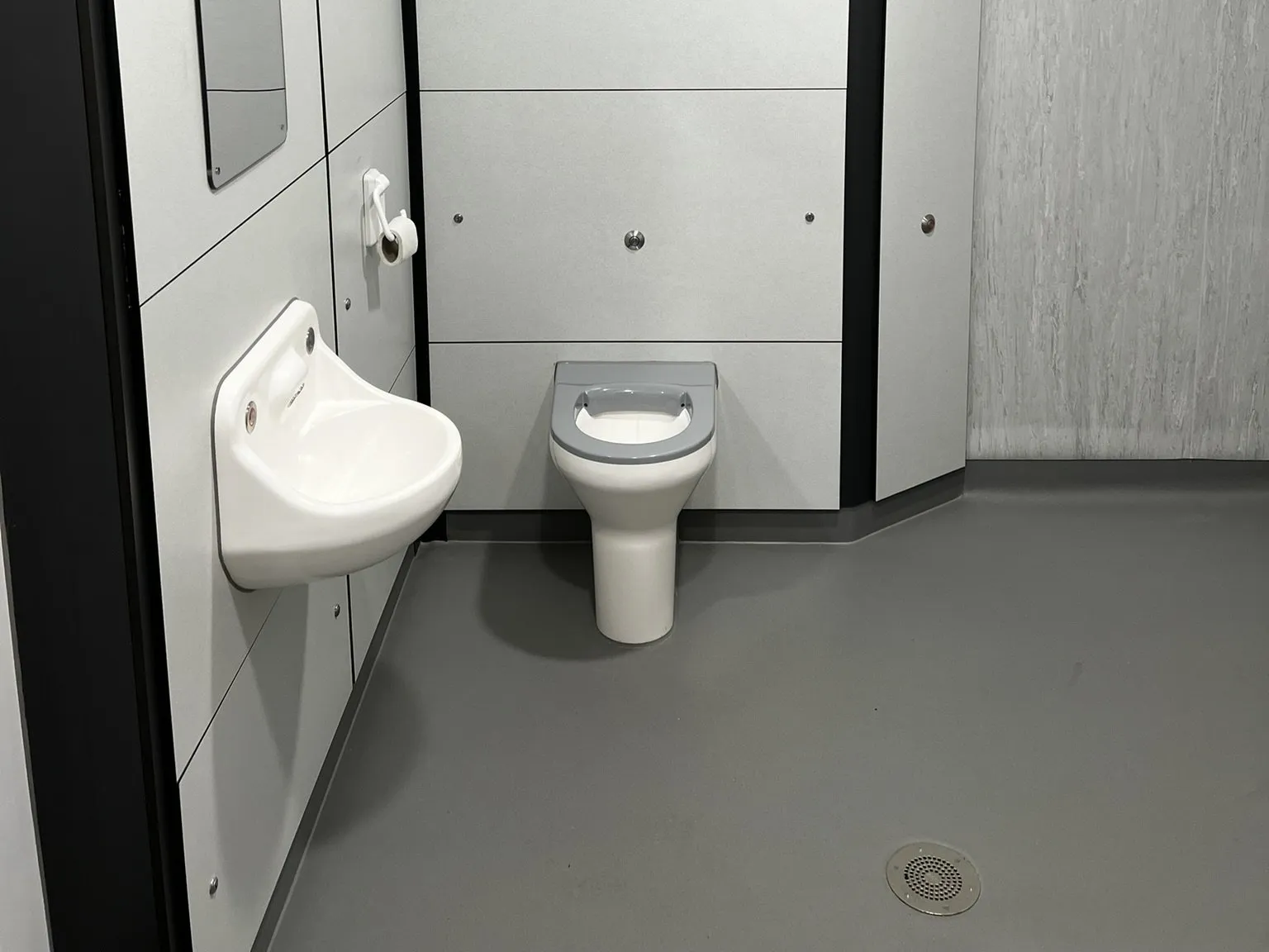 Grey wet-room safety flooring with a floor drain in an en-suite