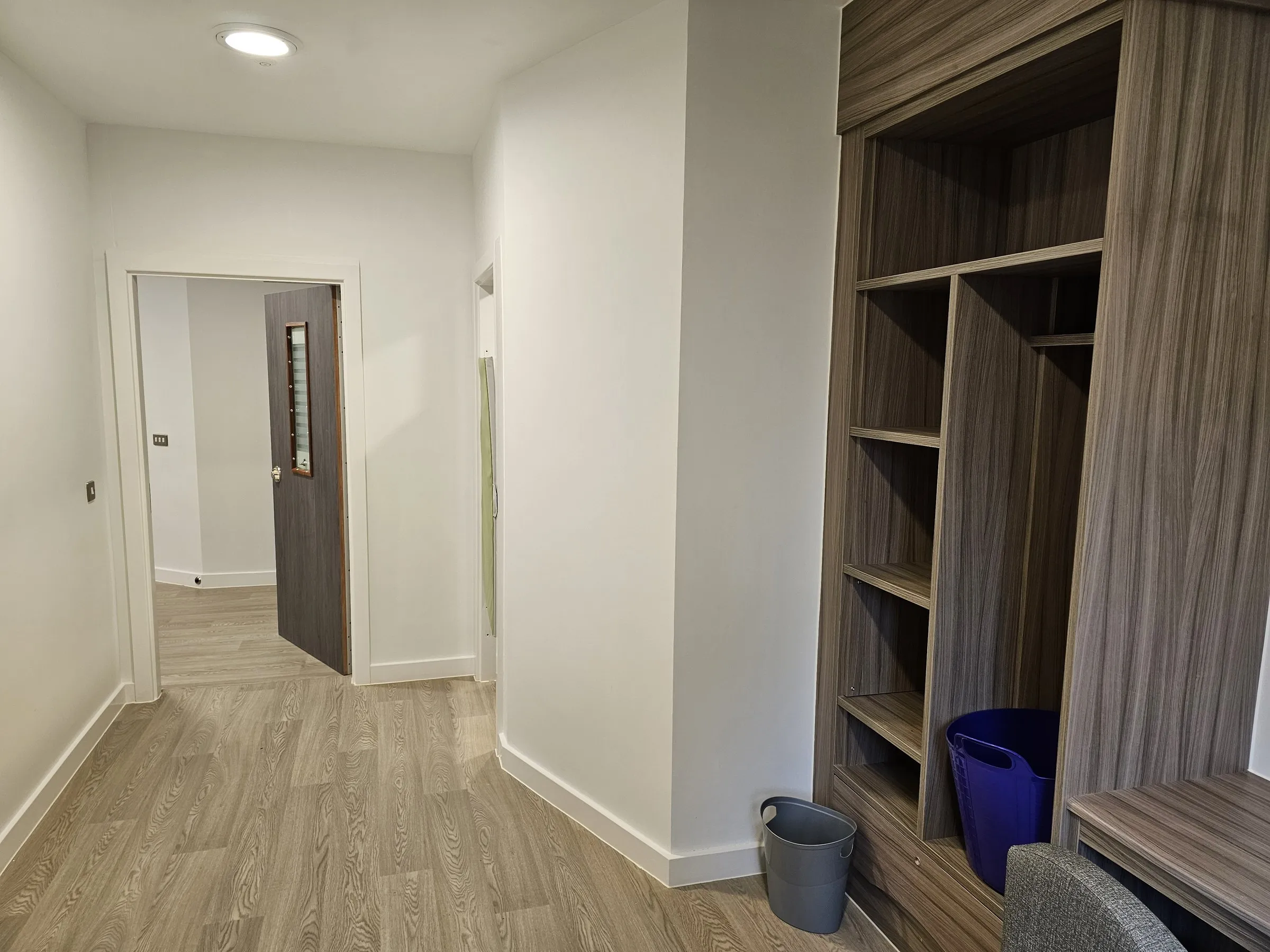 Polyflor Wood FX safety vinyl in an enhanced care bedroom, looking back towards the door past the built-in wardrobe