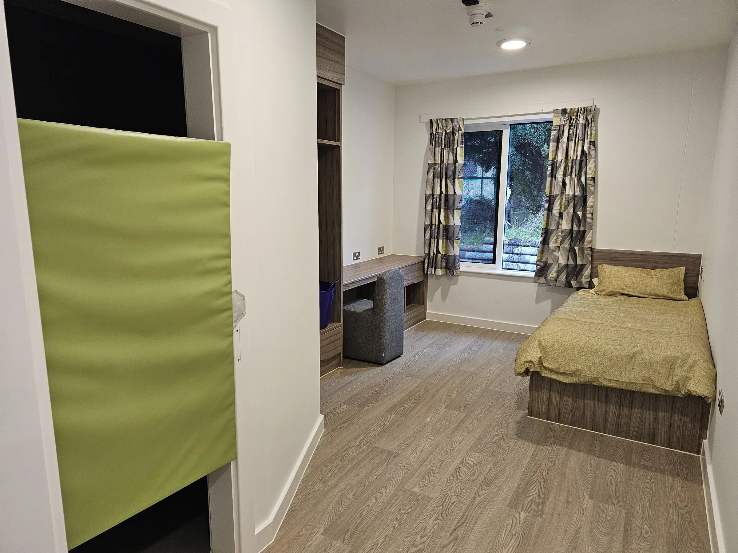 Polyflor Wood FX safety vinyl in an enhanced care bedroom at Cefn Carnau Hospital, beside a padded wall panel
