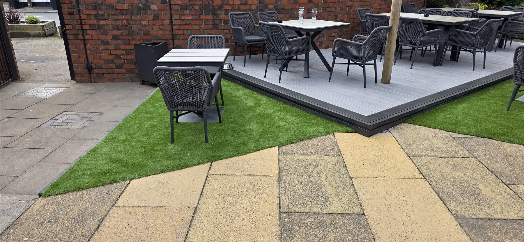 Artificial grass laid up to the raised deck and existing paving in the beer garden