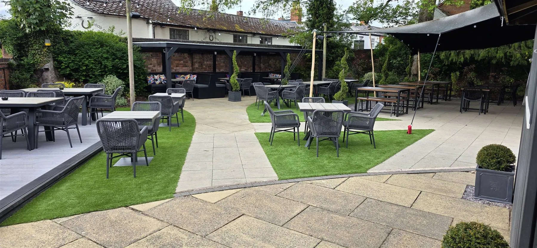Shaped areas of artificial grass between the existing paving across the beer garden