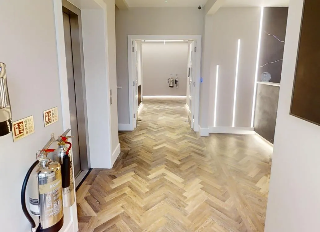 Herringbone LVT with a border plank along the walls in the lift lobby at Abbey House Dental