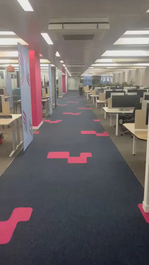 Navy carpet tile walkway running the length of Experian's open-plan floor in Nottingham, with pink inlays repeating between the desks into the distance