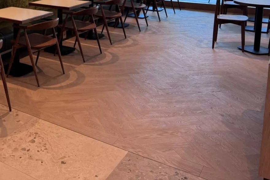 A straight border plank finishing the herringbone where it meets the terrazzo-look tiles