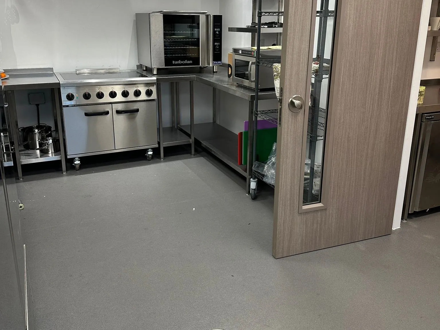 Grey safety vinyl across the kitchen floor, beneath the stainless steel cooking line