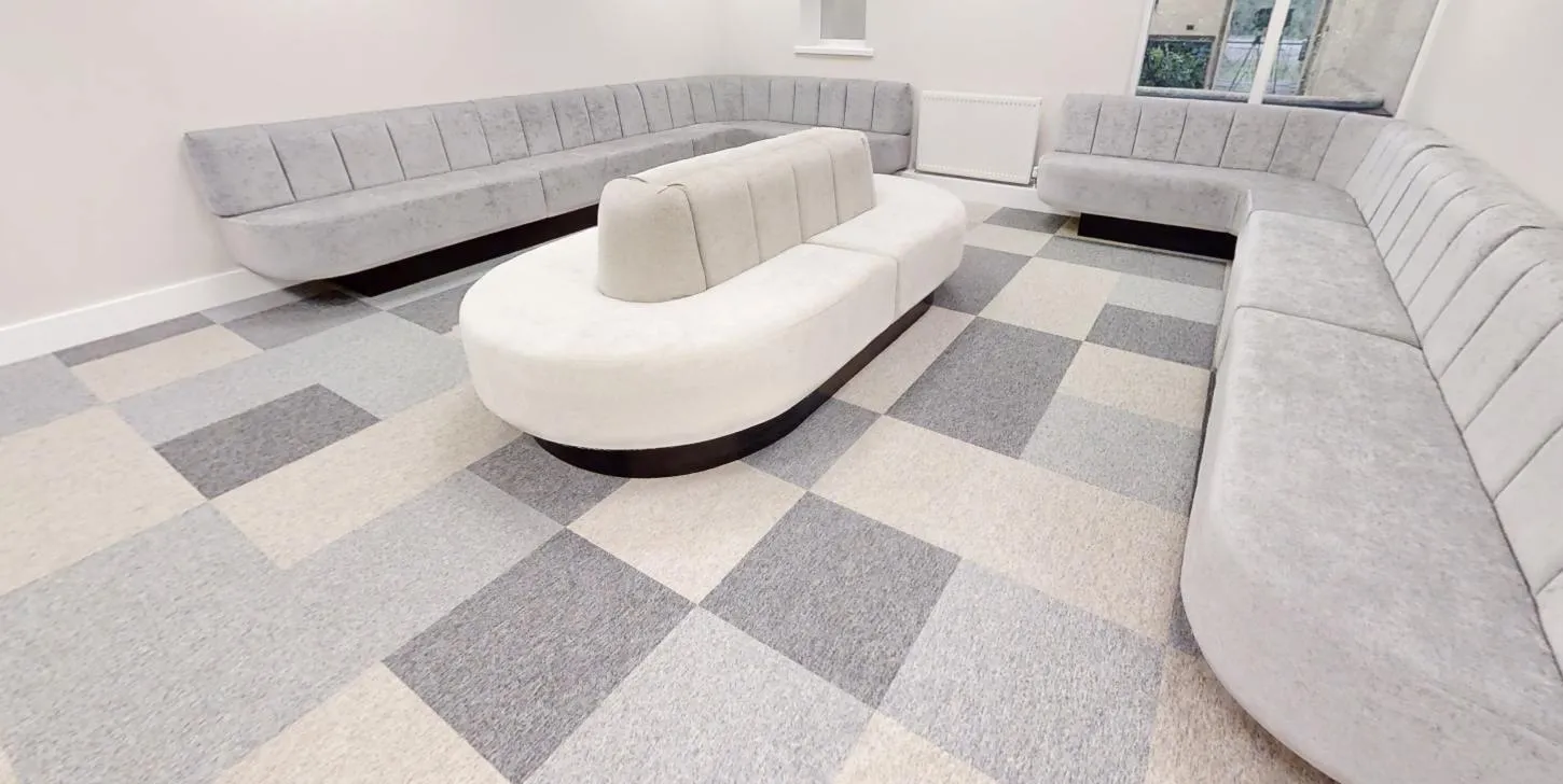 Carpet tiles in mixed tones beneath curved banquette seating in the lounge at Abbey House Dental