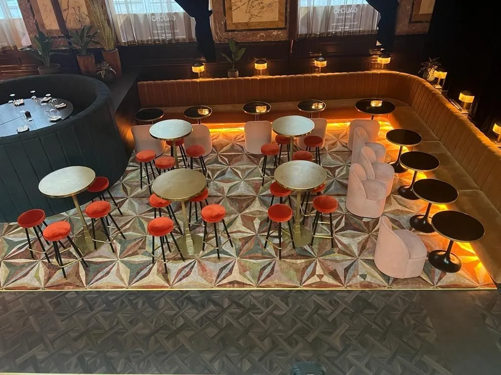 Geometric inset carpet in the bar seating area, edged in brass, with Amtico basket weave around it
