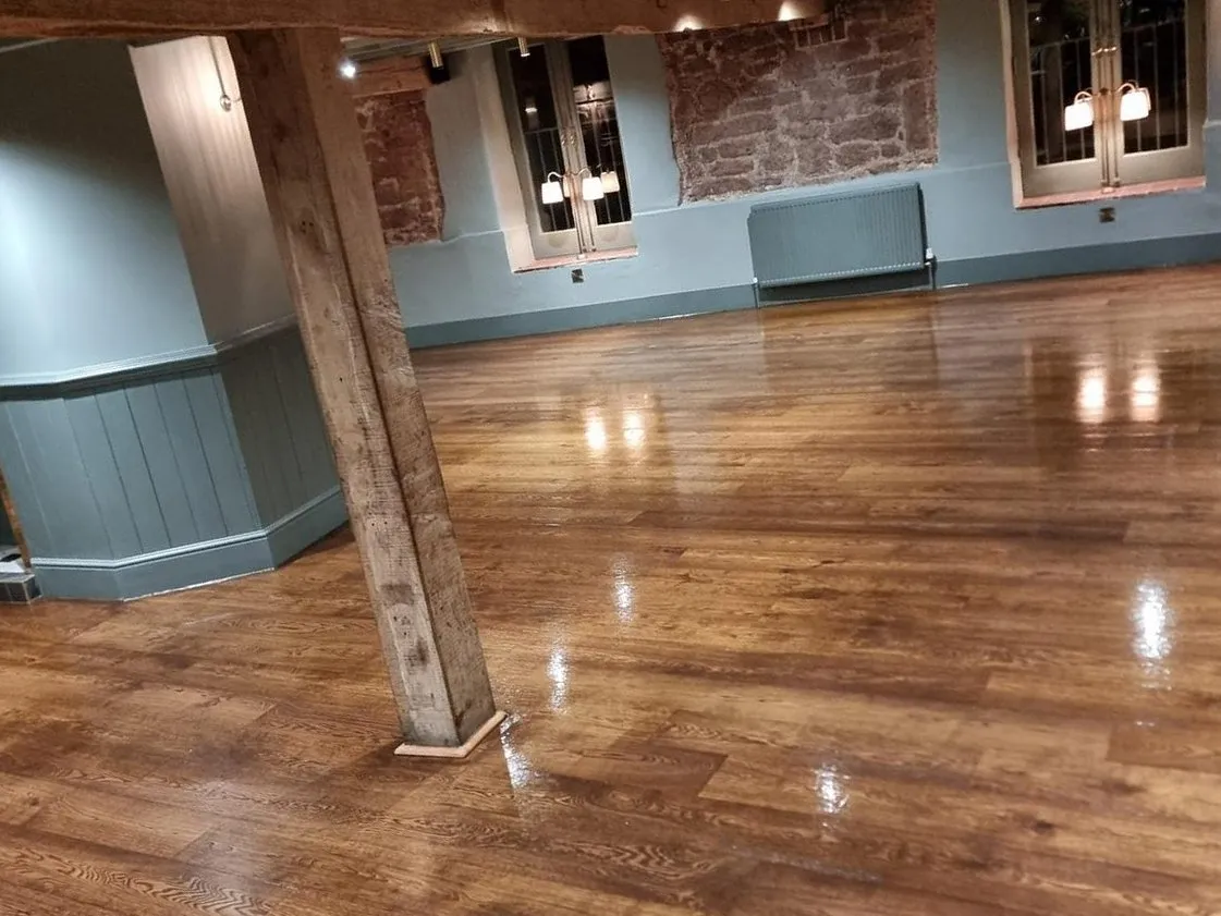 Oak boards with a high-gloss finish across a restaurant dining room in Exeter, past a timber post towards the windows