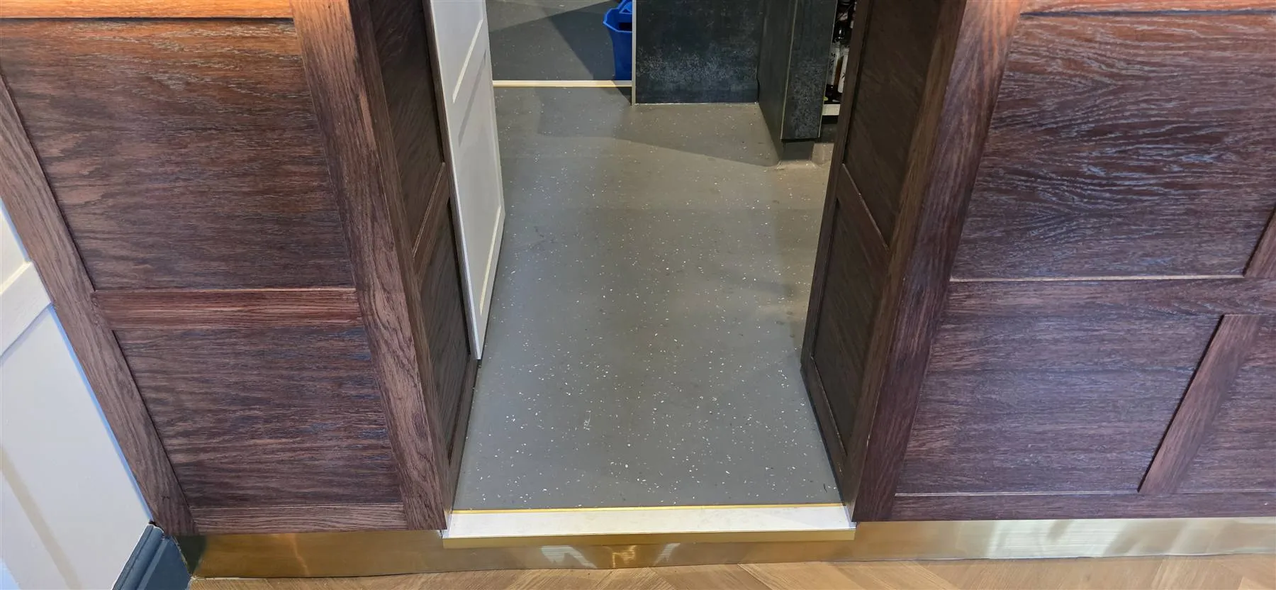 Altro safety flooring behind the bar, meeting a brass-edged threshold at the timber-panelled bar