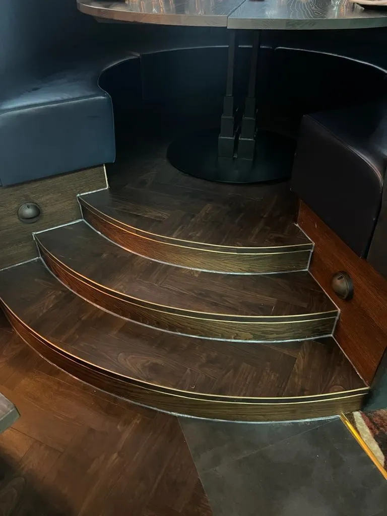 Curved steps in dark timber-effect Amtico, edged in brass trim
