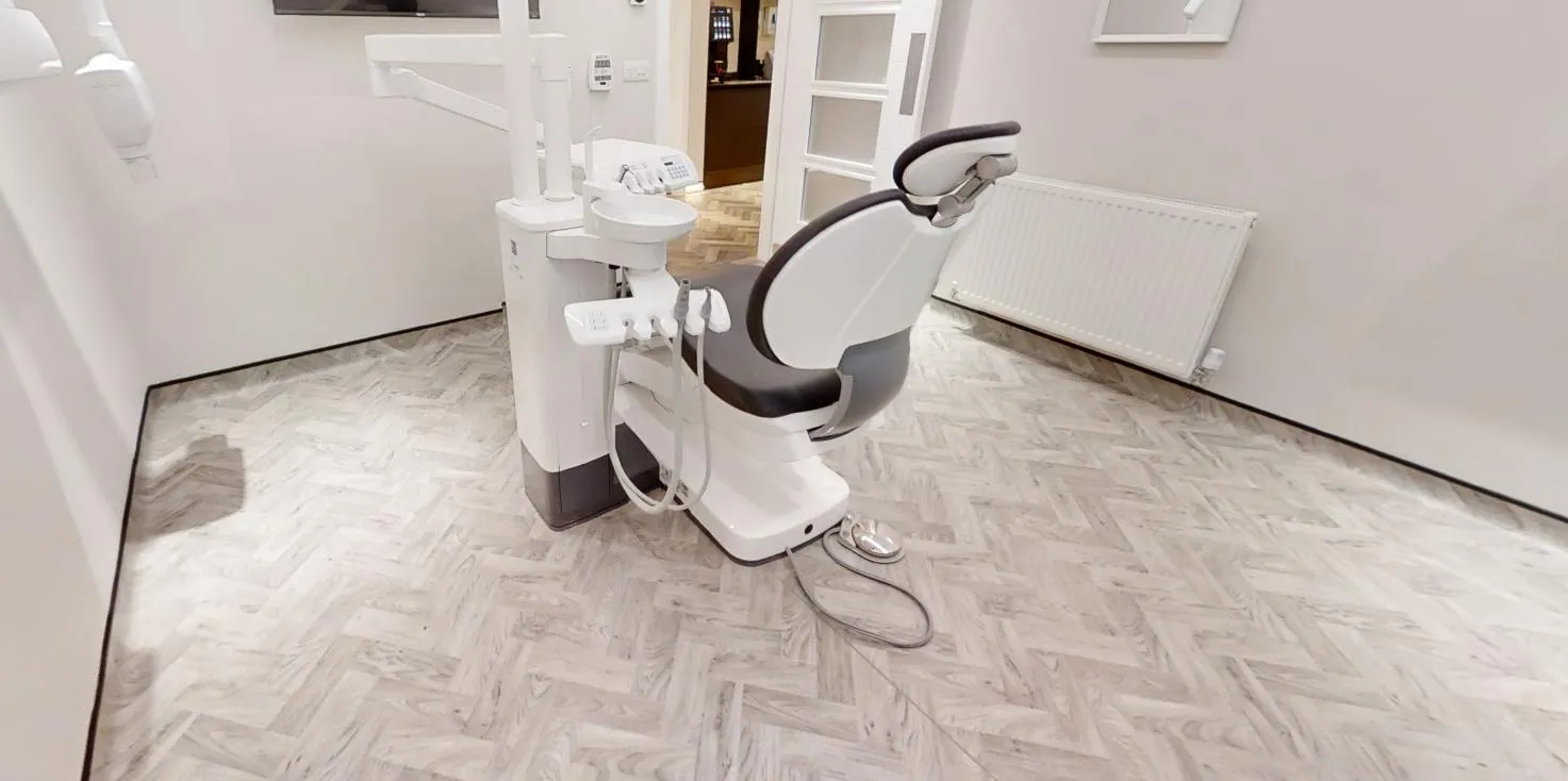 Pale herringbone-effect sheet vinyl in a treatment room, coved up the walls